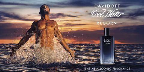 Un uomo senza maglietta emerge dal mare con le braccia aperte. Il cielo è dipinto di tonalità arancioni e viola, suggerendo un tramonto o un'alba. In primo piano, si vede una bottiglia di profumo Davidoff Cool Water Reborn. Il testo recita "La nuova fragranza cult".