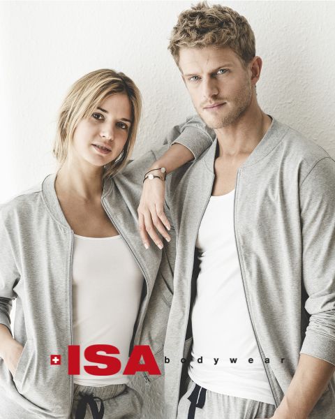 Una donna e un uomo sono in piedi uno accanto all'altro. Entrambi indossano felpe grigie abbinate sopra top bianchi e pantaloni grigi. La donna ha la mano sulla spalla dell'uomo. In basso nell'immagine si vede il logo di "ISA Bodywear".