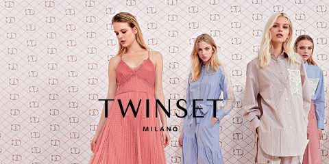 Quattro modelle posano davanti a uno sfondo a motivi indossando abiti diversi, tra cui un abito rosa e camicie a righe blu. Al centro spicca la scritta "Twinset Milano".