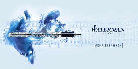Una lussuosa penna stilografica argentata con motivi intricati è circondata da vortici di inchiostro blu. Lo sfondo mostra un elegante paesaggio urbano. Sono visibili il logo "Waterman Paris" e il testo "Scopri di più".