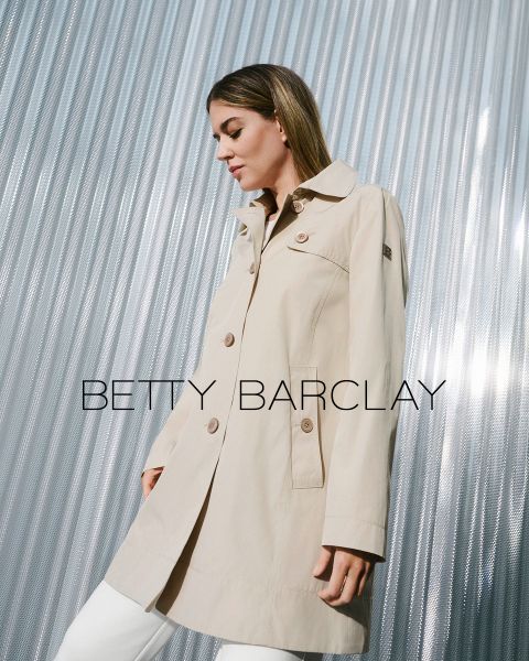 Una donna con un trench beige è in piedi davanti a uno sfondo metallico ondulato. Il cappotto ha grandi bottoni e un colletto. Il testo "Betty Barclay" è sovrapposto all'immagine. Sembra soddisfatta e guarda a destra.