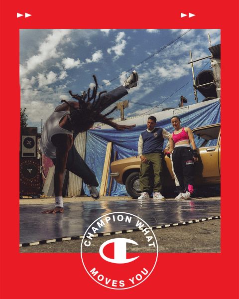 Un breakdancer esegue un headspin su un tappetino all'aperto, mentre un uomo e una donna lo guardano. Sono in piedi accanto a un'auto d'epoca di fronte a uno sfondo urbano con teloni blu e cielo nuvoloso. Una cornice rossa con il testo e il logo "Champion What Moves You" circonda l'immagine.