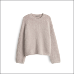 Ein hellbeiger, flauschiger, langärmeliger Pullover mit Rundhalsausschnitt, der vor einem schlichten weißen Hintergrund steht.