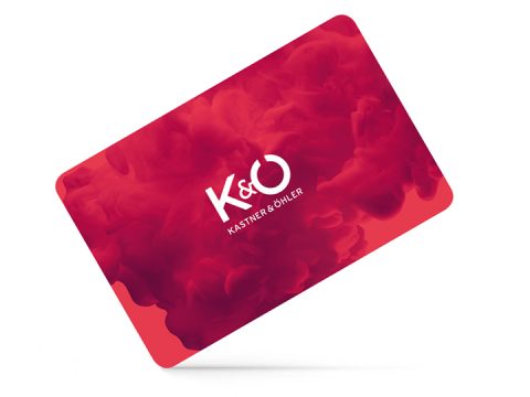 Una carta regalo rossa con le lettere bianche "K&O" e sotto la scritta "KASTNER & ÖHLER". Lo sfondo presenta un motivo di fumo rosso vorticoso.