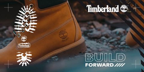 Primo piano di uno stivale Timberland su terreno roccioso, con il logo Timberland e la frase "BUILD FORWARD" sul lato destro. Lo stivale è marrone chiaro e ha una suola robusta, che emana un look da outdoor e avventura.