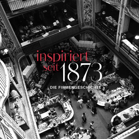 Una foto in bianco e nero di un affollato grande magazzino a più piani visto dall'alto, che mostra acquirenti e vari banconi. Il testo in rosso e bianco recita "ispirati dal 1873 - la storia dell'azienda".