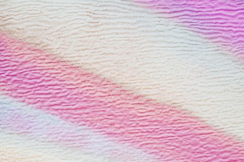 Immagine astratta con linee morbide e ondulate nei toni del rosa, del viola e del bianco. La texture ricorda una superficie increspata, creando un motivo rilassante e stratificato.