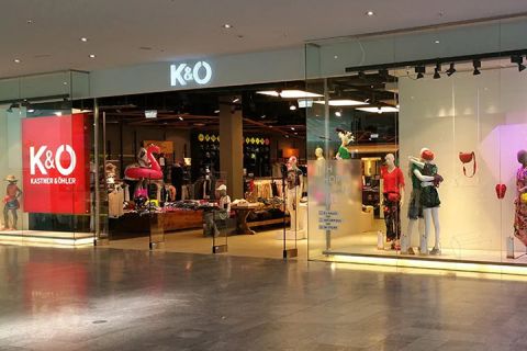 Vetrine di Kastner & Öhler con ampie vetrate che espongono manichini vestiti. All'interno del negozio si intravedono appendiabiti e una selezione di abbigliamento. Il logo K&O risplende ben visibile sopra l'ingresso.