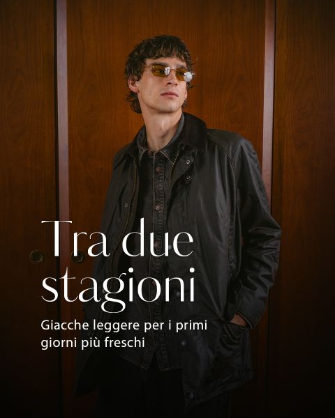 Un uomo con occhiali da sole e una giacca scura si trova di fronte a delle porte di legno. Sull'immagine è presente un testo in italiano che parla di giacche leggere per le giornate più fresche.
