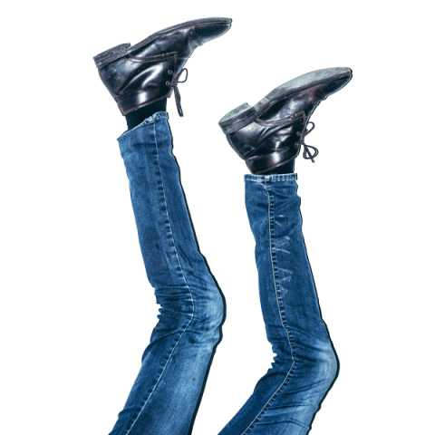 Un paio di gambe in blue jeans e scarpe nere spuntano in aria su uno sfondo bianco, creando l'illusione di essere a testa in giù.
