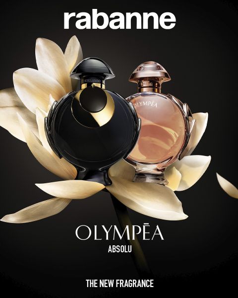 Due flaconi di profumo Rabanne Olympéa ABSOLU, uno nero e uno rosa, sono esposti davanti a un fiore bianco in fiore su uno sfondo scuro. Il testo recita: "Rabanne OLYMPÉA ABSOLU - LA NUOVA FRAGRANZA".