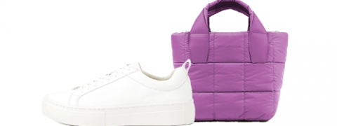 Un primo piano di una sneaker bianca con lacci accanto a una piccola borsa a mano trapuntata viola con manici.