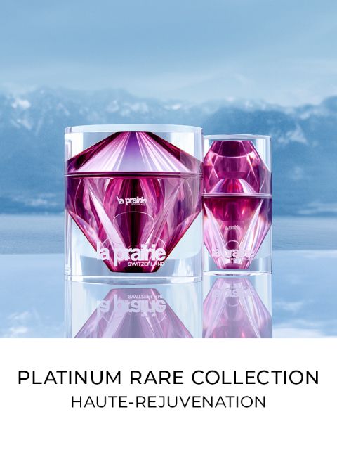 Due vasi lussuosi e sfaccettati in tonalità rosa e viola si stagliano su uno sfondo di cielo blu e montagne. Sotto i vasi si legge il testo "Platinum Rare Collection Haute-Rejuvenation".