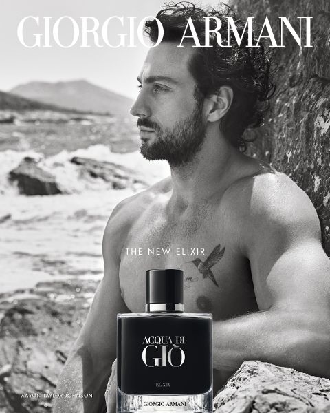 La pubblicità in bianco e nero di Acqua di Giò Elixir di Giorgio Armani mostra un uomo a torso nudo con capelli ricci seduto su scogliere rocciose in riva al mare, che guarda in lontananza. In primo piano si vede il flacone del profumo.