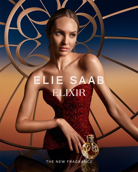 Persona in abito rosso di paillettes che posa con il profumo Elie Saab Elixir. Lo sfondo presenta un design stilizzato e circolare con una sfumatura di colore dall'arancione al blu. Il testo recita: "Elie Saab Elixir" e "La nuova fragranza".