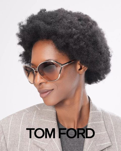Persona con un taglio di capelli afro corto, che indossa grandi occhiali da sole e un blazer gessato grigio. Nell'immagine in basso c'è scritto "Tom Ford". Lo sfondo è semplicemente bianco.