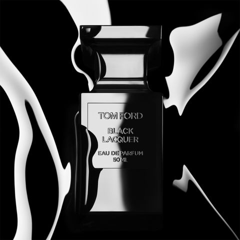 Un elegante flacone di profumo nero con la scritta "Tom Ford Black Lacquer Eau de Parfum 50 ml" è posizionato di fronte a uno sfondo contrastante, bianco e nero, simile a un liquido, conferendo all'insieme un aspetto lussuoso ed elegante.