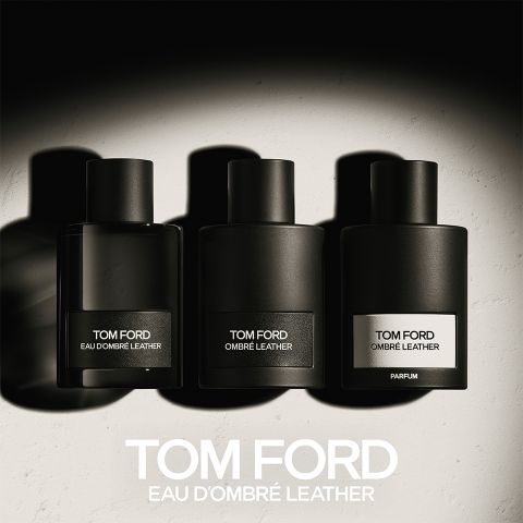 Tre flaconi neri di profumi Tom Ford con le scritte "Eau d'Ombre Leather", "Ombre Leather" e "Parfum" sono allineati. Proiettano ombre su una superficie chiara, sotto c'è scritto in grassetto "TOM FORD EAU D'OMBRE LEATHER".