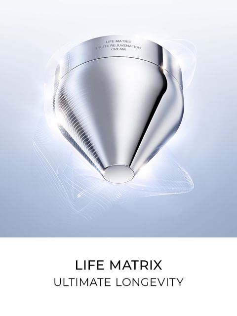 Contenitore cosmetico futuristico argentato con sottili linee luminose intorno, con la scritta "Life Matrix Haute Rejuvenation Cream". Il testo sottostante recita "Life Matrix Ultimate Longevity" su sfondo bianco.