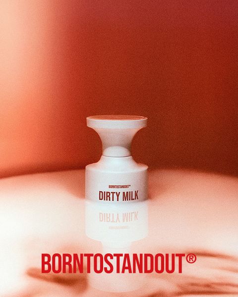 Una bottiglia bianca con la scritta "DIRTY MILK" è posizionata su una superficie riflettente con una calda sfumatura rossa. Sotto, in grassetto rosso, si legge "BORNTOSTANDOUT®".