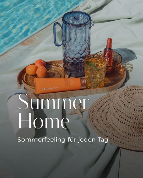 Una scena a bordo piscina con un cappello di paglia, crema solare, albicocche, una brocca di vetro, bevande e un vassoio. Il testo recita: "Summer Home - Sensazione estiva per ogni giorno.