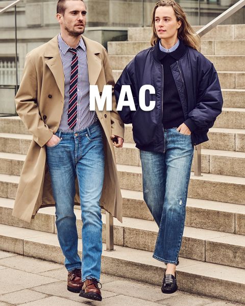 Un uomo in trench e una donna in giacca blu navy scendono una scala di pietra in blue jeans. Sopra l'immagine c'è la scritta "MAC".