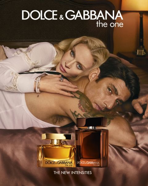 Un uomo senza maglietta e una donna in bikini bianco sono sdraiati su un galleggiante bianco vicino ad acque rocciose e blu. In primo piano ci sono due flaconi di profumo azzurri di Dolce & Gabbana. Il testo recita "Dolce & Gabbana Light Blue".