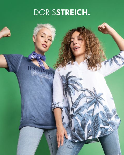 Due donne posano con sicurezza in abiti in bianco e nero con accenti verdi, tra cui un gilet imbottito, un cappello e scarpe, davanti a uno sfondo scuro con il testo "DORIS STREICH" sopra di loro.