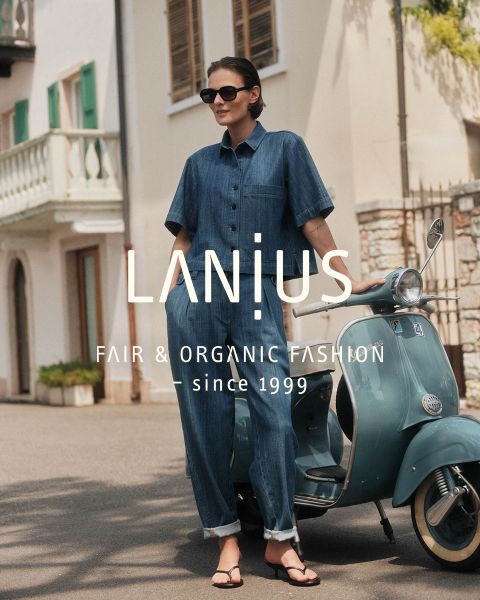 Una donna con un lungo abito blu scuro è seduta tra formazioni rocciose stratificate. Il testo sovrapposto recita: "LANIUS FAIR & ORGANIC FASHION - dal 1999.