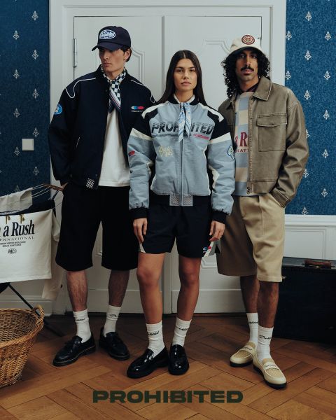 Due uomini siedono su un ponte di legno nell'erba alta e giocano a backgammon. Uno indossa un berretto rosso, una camicia a quadri e jeans, l'altro un berretto marrone castagna, una giacca verde oliva e pantaloni scuri. Sopra di loro c'è scritto "PROIBITO".