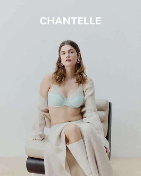 Una donna in sottoveste nera di pizzo e con occhiali da sole è seduta su una barca vicino a un fiume cittadino, con edifici e alberi sullo sfondo. La parola "CHANTELLE" è visibile nella parte inferiore dell'immagine.