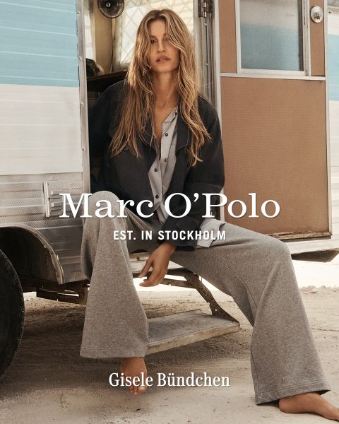 Una donna con una camicia a quadri, pantaloncini neri e stivali marroni è in piedi davanti a una parete di legno consumata. Il testo recita: "Marc O'Polo EST. IN STOCKHOLM Gisele Bündchen.