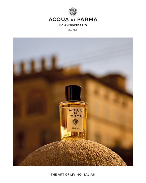 Una griglia di nove quadrati presenta la nuova fragranza Zafferano di Acqua di Parma. Ogni quadrato mostra un frammento del flacone di profumo nero su uno sfondo dorato con accenti rossi e dorati. Il testo recita: "Scopri il nuovo Zafferano, Firme del Sole".