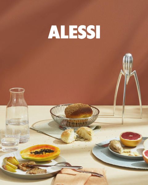 Due moderni portauovo geometrici con uova sono posizionati su un vassoio riflettente, insieme a una ciotola di vetro e un cucchiaio. In basso al centro dell'immagine si legge "ALESSI" in grassetto.