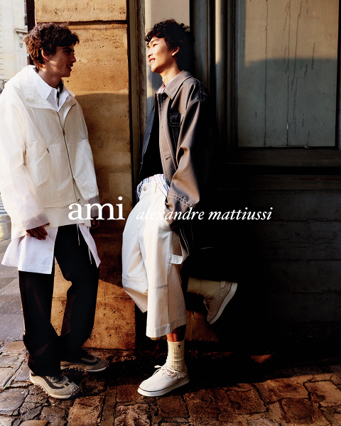 Tre persone vicine in abiti eleganti, una tiene in mano un drink. Il testo "ami alexandre mattiussi" è sovrapposto all'immagine in lettere bianche. I loro volti non sono visibili.