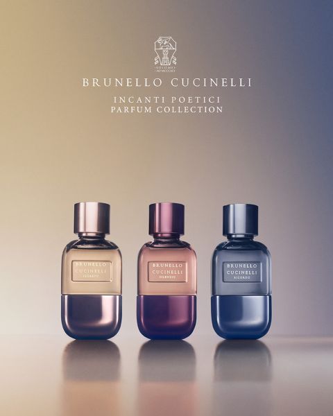 Sei flaconi di profumo di Brunello Cucinelli sono disposti in fila sopra un letto di fiori colorati e piante verdi. Il testo sopra recita "Brunello Cucinelli" e sotto: "Incanti Poetici Parfum Collection".