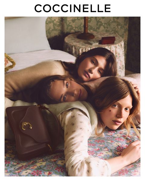 Donna in abito marrone seduta su una sedia bianca in riva al mare e tiene in mano una borsa gialla Coccinelle. Il logo Coccinelle si trova in alto.