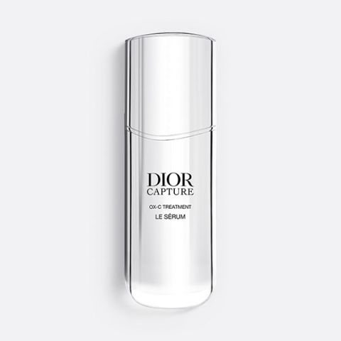 Una bottiglia sottile e traslucida di Dior Capture OX-C Treatment Le Sérum. La bottiglia è alta e sinuosa, con un design minimalista e testo nero sul davanti. Su uno sfondo grigio chiaro.