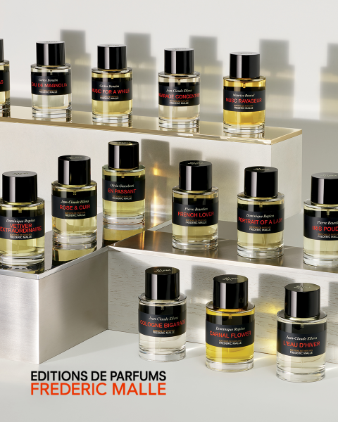 Primo piano di una persona in costume da bagno bianco, con alberi sfocati sullo sfondo. Un grande testo sopra l'immagine recita "CARNAL FLOWER". Nel testo si menzionano Dominique Ropion e Editions de Parfums Frederic Malle.