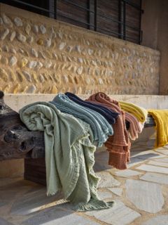 Quattro cuscini rettangolari verde oliva con un delicato bordo arricciato sono disposti su due file davanti a uno sfondo con una sfumatura grigio-bianca.