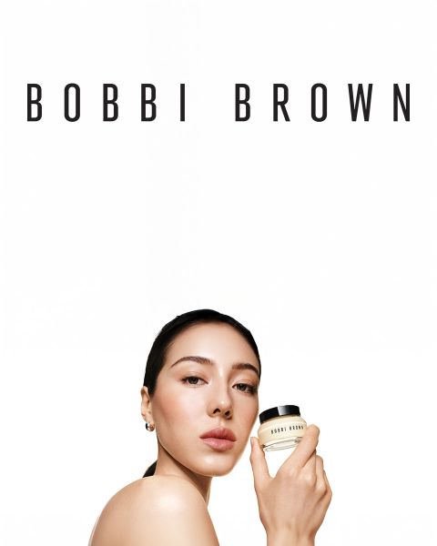 Una selezione di ombretti in crema a lunga tenuta di Bobbi Brown in varie tonalità, presentati orizzontalmente su una superficie strutturata. Ogni stick è aperto, rivelando i colori cremosi. Il marchio è visibile sui tappi.