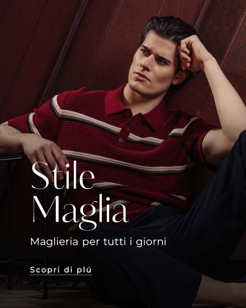 Un uomo con una polo a righe rosse e pantaloni scuri è seduto pensieroso contro una parete di legno. Il testo italiano pubblicizza maglieria alla moda.