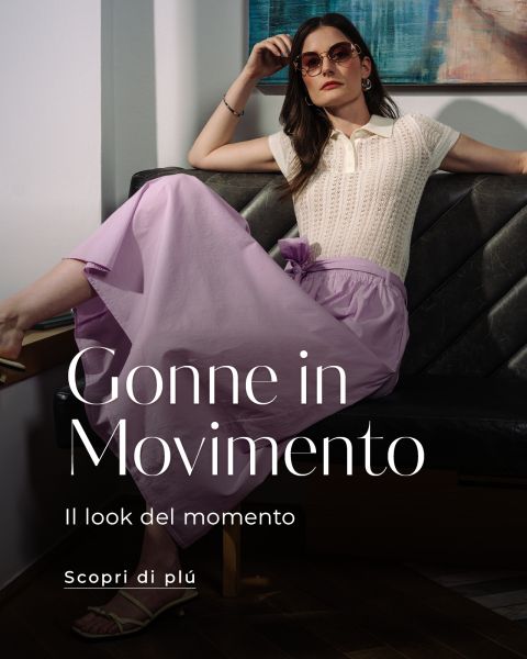 Una donna con occhiali da sole e un top color crema con una gonna viola posa su un divano. Il testo dice: "Gonne in Movimento. Il look del momento. Scopri di più.