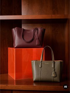 Due borse tote in pelle, una bordeaux e una verde oliva, esposte su scaffali di legno insieme a un blocco acrilico arancione.