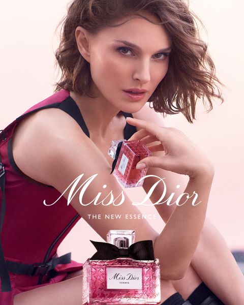 Un flacone di profumo Dior dorato, circondato da farfalle dorate fluttuanti, un fiocco rosa e delicati fiori bianchi con il testo "DIOR Because I Adore You".