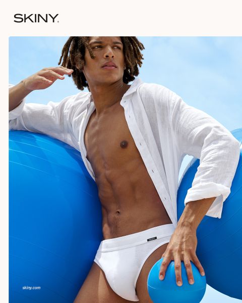 Un uomo muscoloso e alla mano guarda in basso. Ha un maglione rosso sulla spalla e indossa biancheria intima verde. Lo sfondo è rosso scuro e la parola "SKINY" è visualizzata in basso.