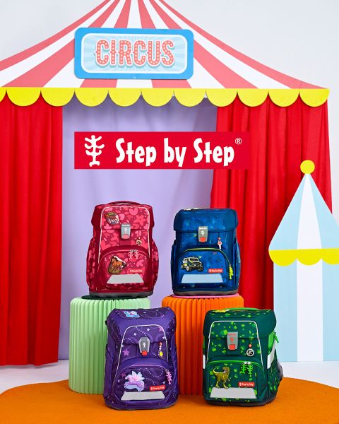 Davanti a una tenda da gioco, due bambini siedono a terra, ognuno con uno zaino colorato. A sinistra si legge il testo "Si adatta sempre, garantito!". Sullo sfondo si vedono scaffali con giocattoli e decorazioni.