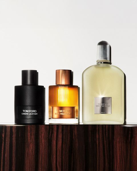 Un'immagine in bianco e nero che mostra un uomo e una donna con cappelli a tesa larga. Sono in piedi uno di fronte all'altra, molto vicini. Nell'angolo in basso a sinistra c'è una bottiglia con l'etichetta "Tom Ford Eau d'Ombre Leather". Il nome del marchio è ben visibile.