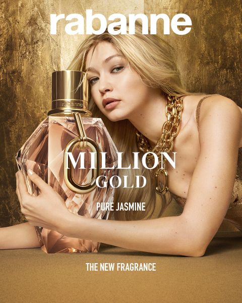 Una donna in abito dorato e una collana vistosa posa con un grande flacone di profumo sfaccettato con la scritta "Million Gold Pure Jasmine" di Rabanne. Lo sfondo è dorato e in basso si legge "LA NUOVA FRAGRANZA".