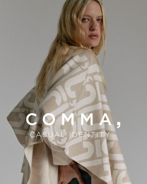 Una donna con lunghi capelli biondi indossa un poncho a motivi beige e bianco. È in piedi di lato e guarda oltre la sua spalla. Il testo sull'immagine è: "COMMA, CASUAL IDENTITY".